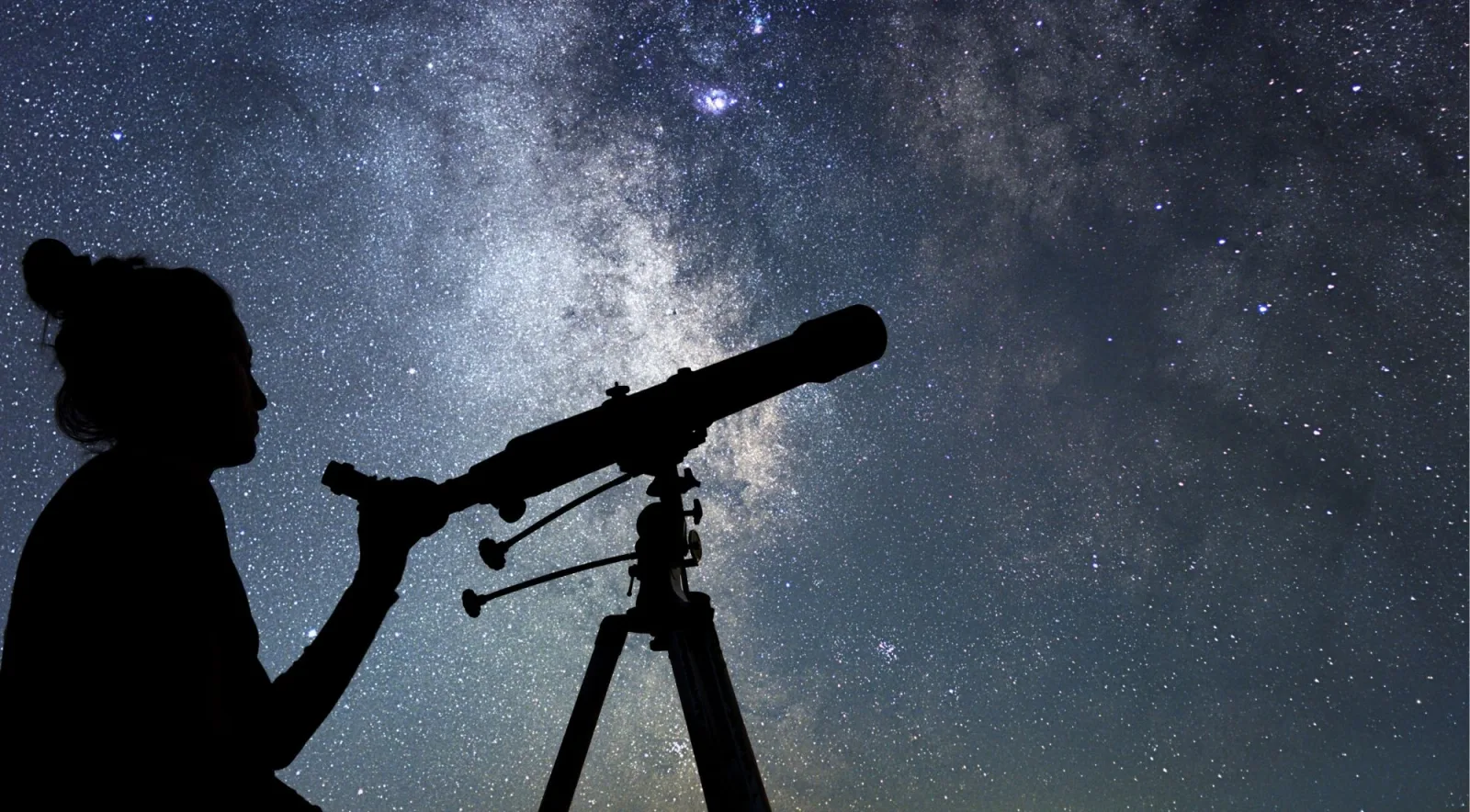 Stargazer silhouetted against the Milky Way while looking through a telescope at Mauna Kea