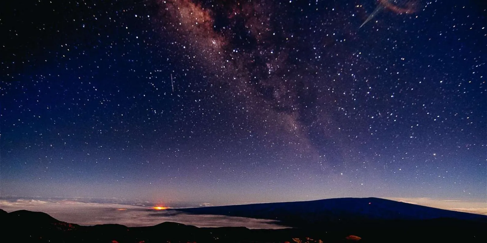 Sunrise view from Mauna Kea summit with cloud sea below and observatory domes