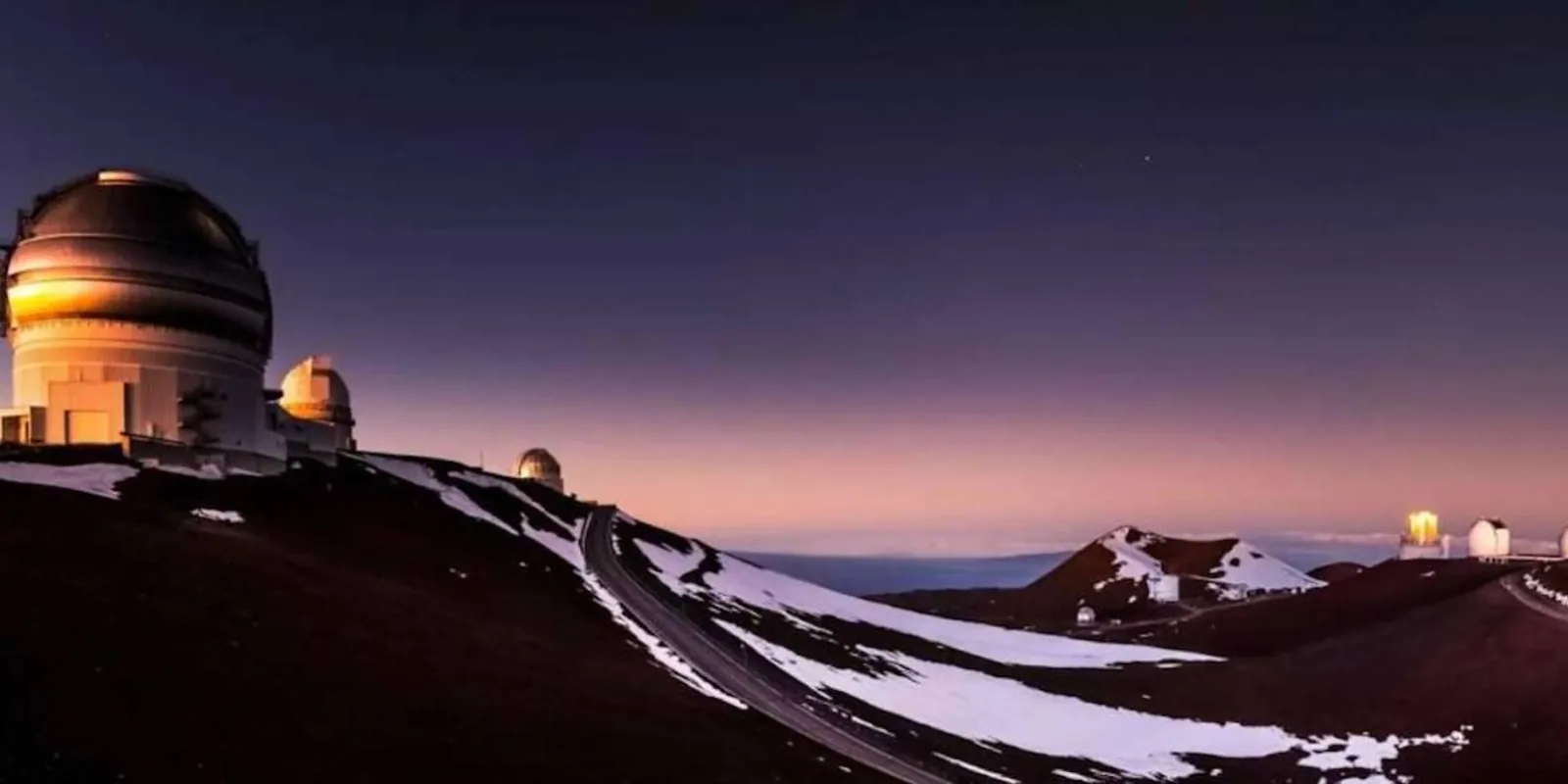 Mauna Kea summit at night — observatory domes lit against the Milky Way