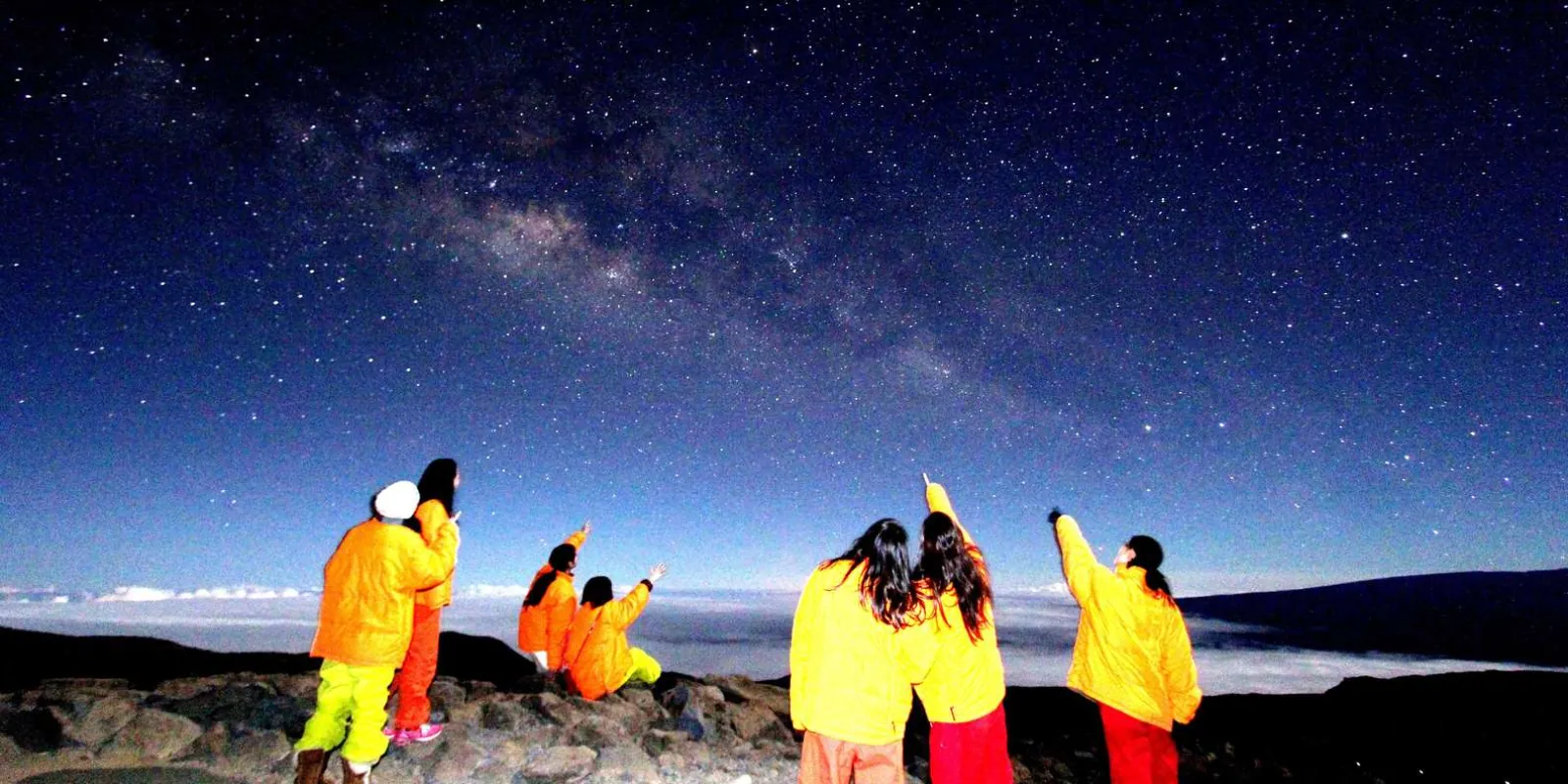 Guests in parkas gathered around telescope eyepiece on the summit